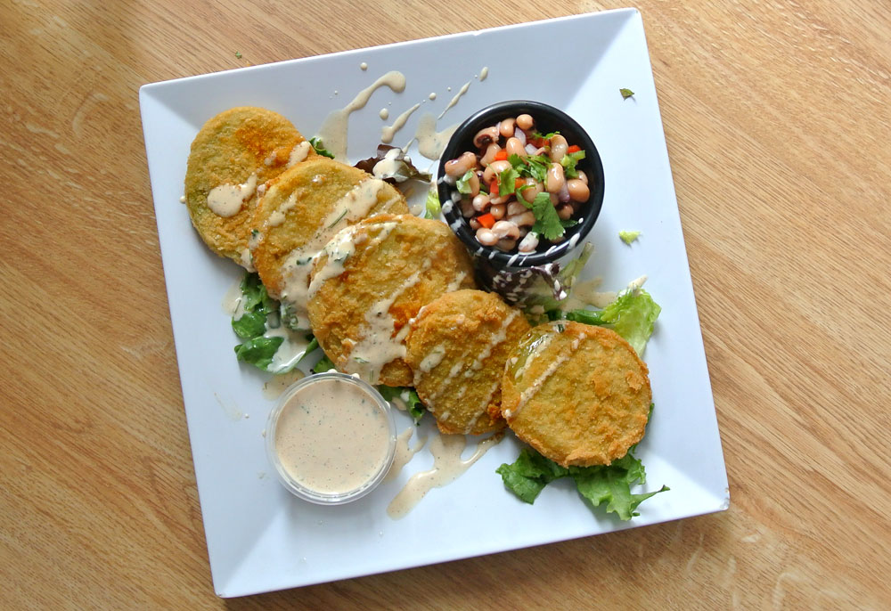 A staple of Southern food, fried green tomatoes are green tomato slices, dipped in batter, fried, and seasoned.
