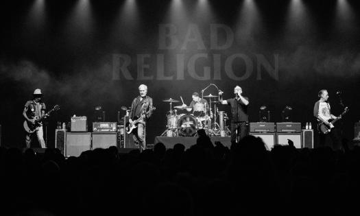 The five members of Bad Religion, performing on stage and seen in black and white