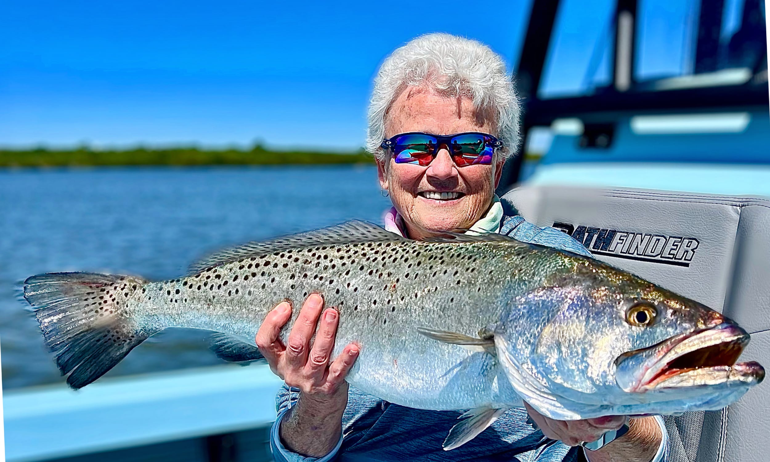 A woman displays a trout caught during a fishing trip with Coastal Fish Charters