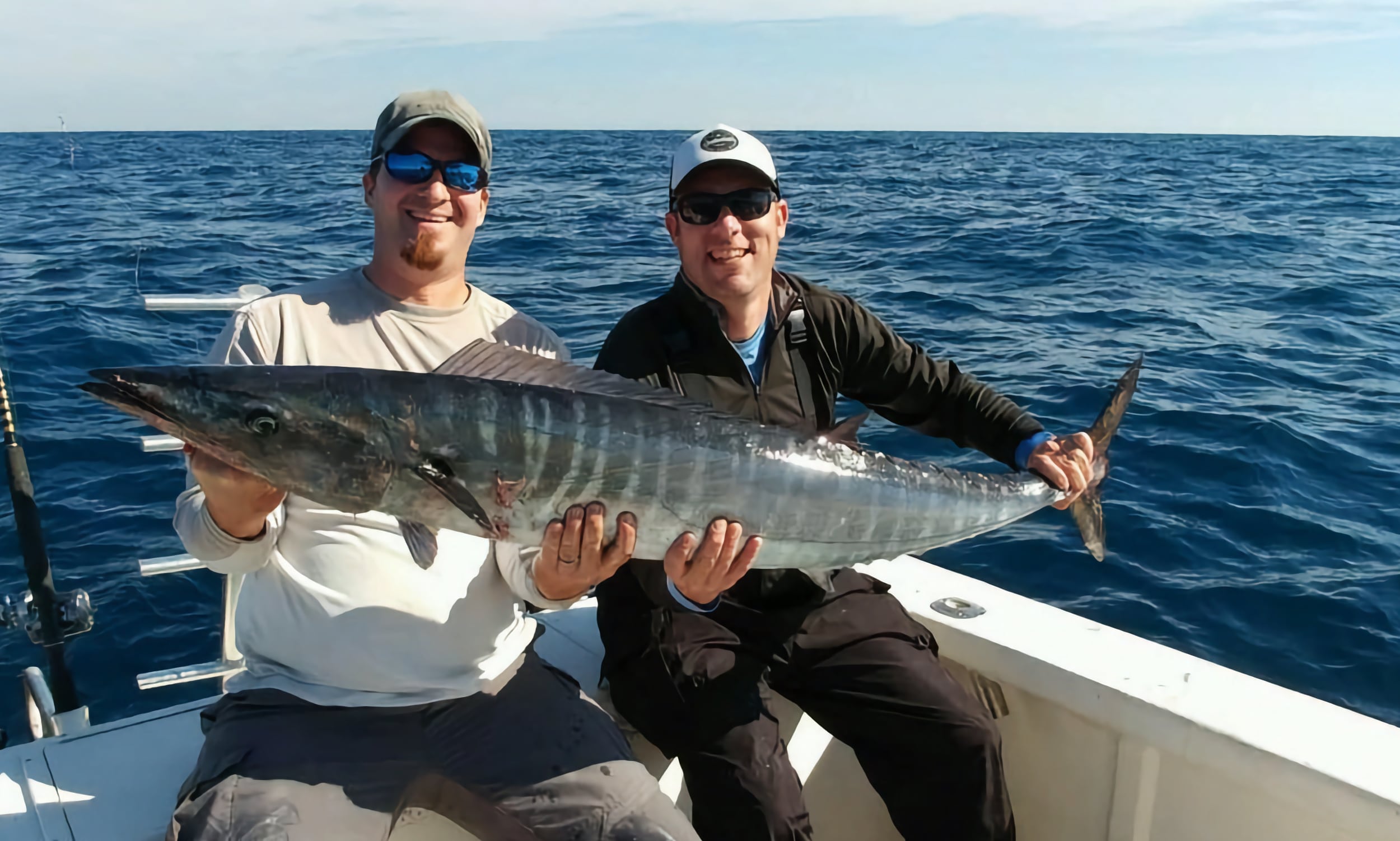 Two fishermen displaying a wahoo caught with Get Schooled Fishing Charters