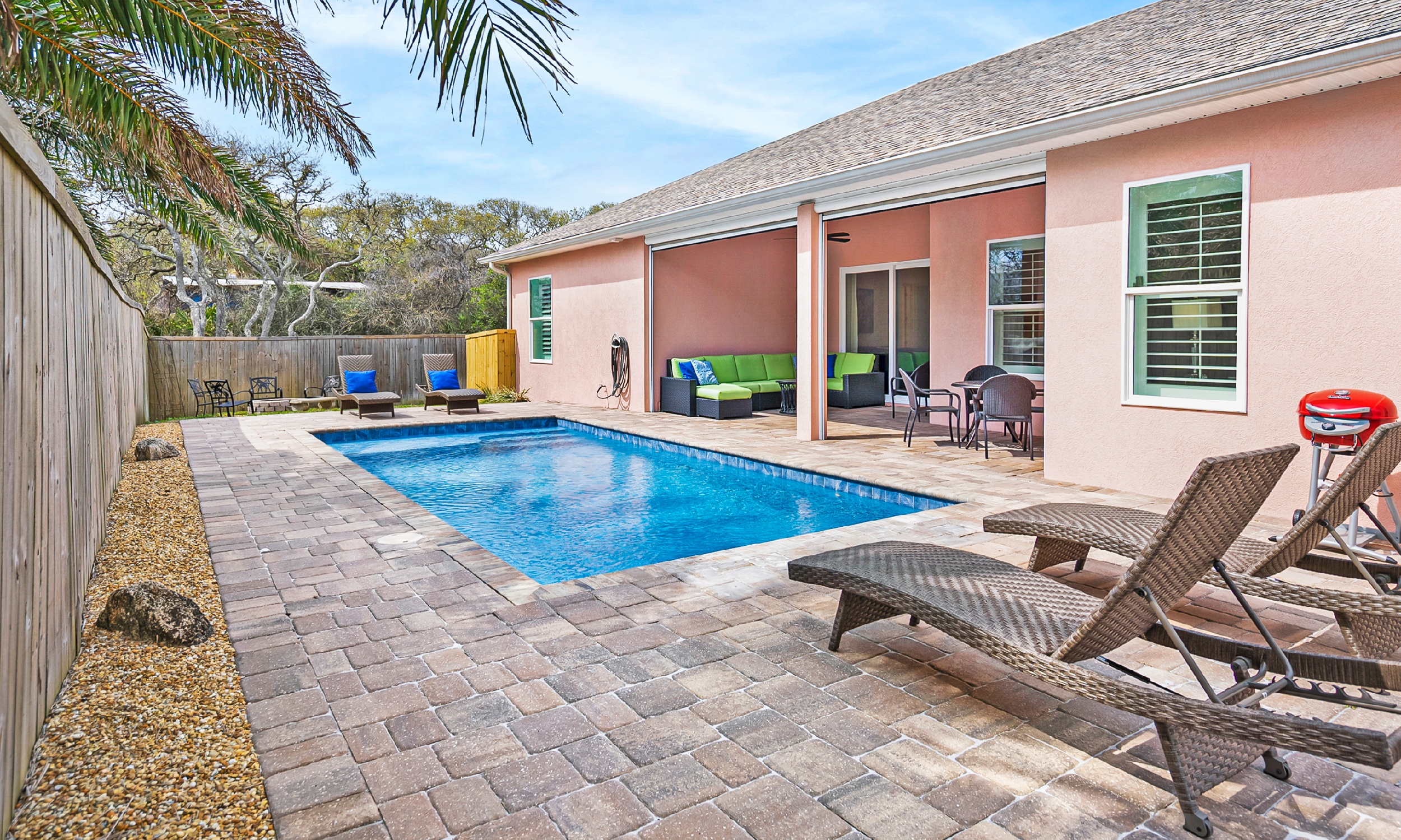 This pink vacation home has a private yard and a pool and deck