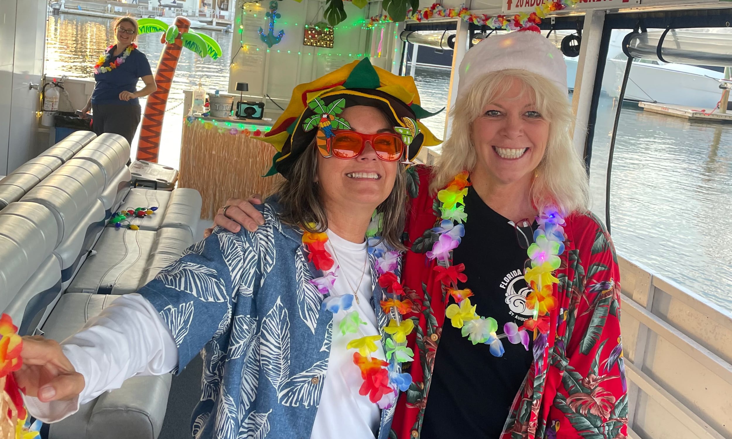 Two women dressed with bright shirts and leis to celebrate Jimmy Buffett