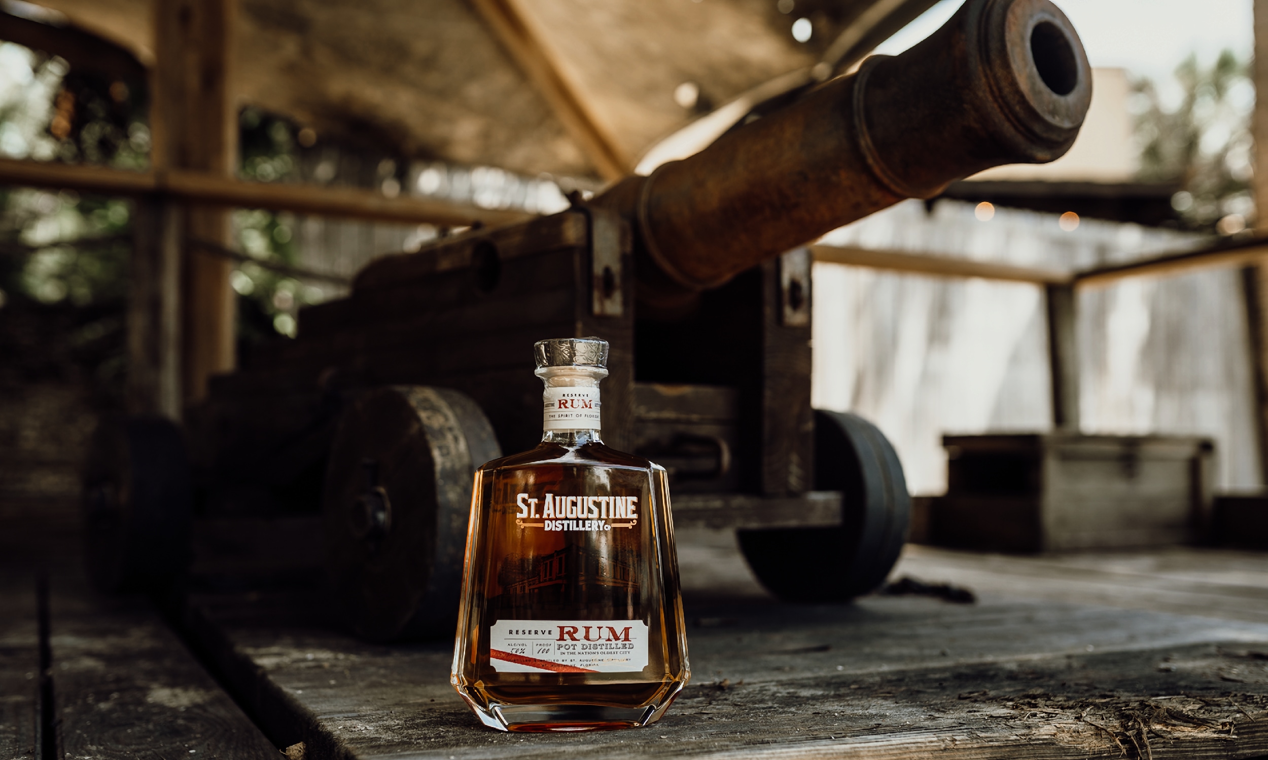 A bottle of St. Augustine Distillery 2024 Reserve Rum, next to a cannon in St. Augustine