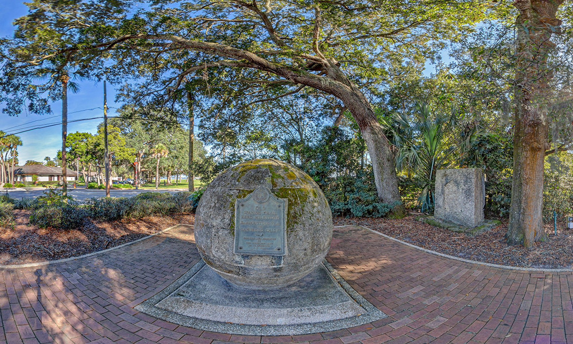 A round sculpture make out of stone sitting on a brick walkway