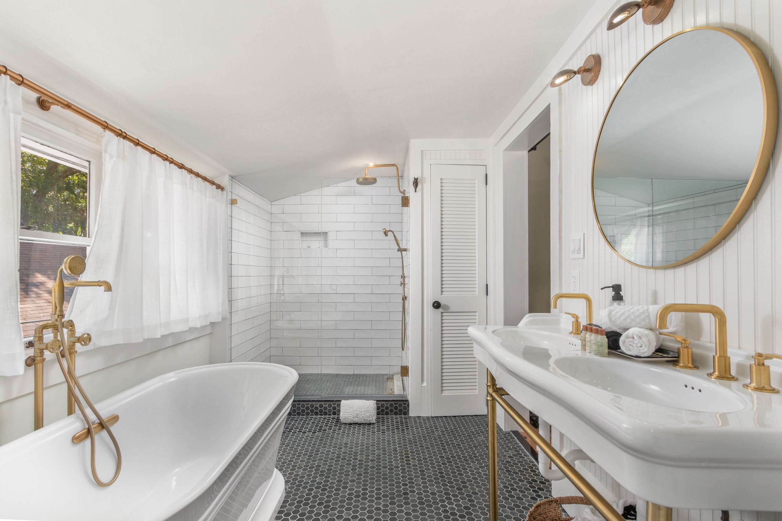 This luxurous bath has a double sink, soaking tub, and large shower, all with brass accents