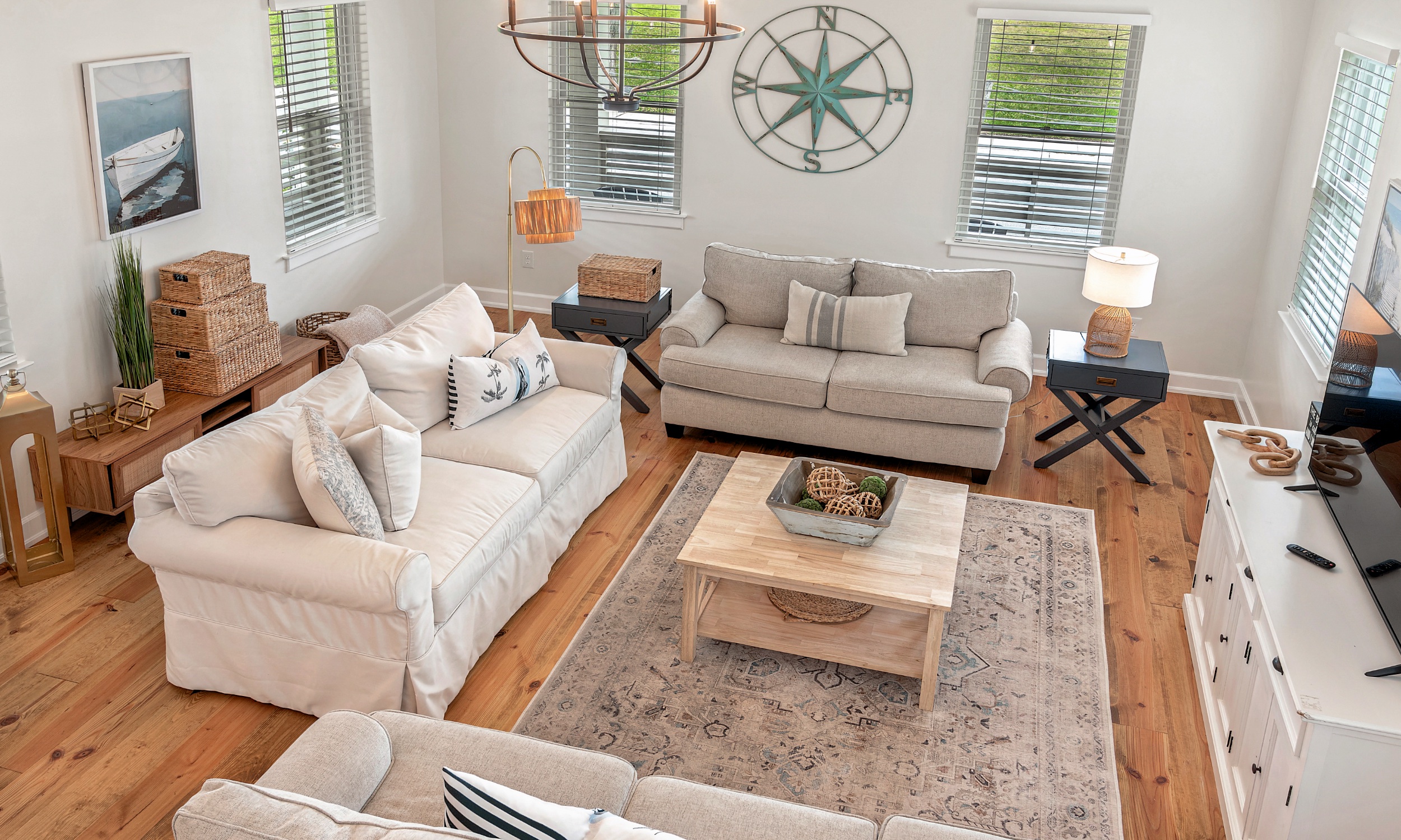 This living room features three sofas, a wood floor, and coastal decor