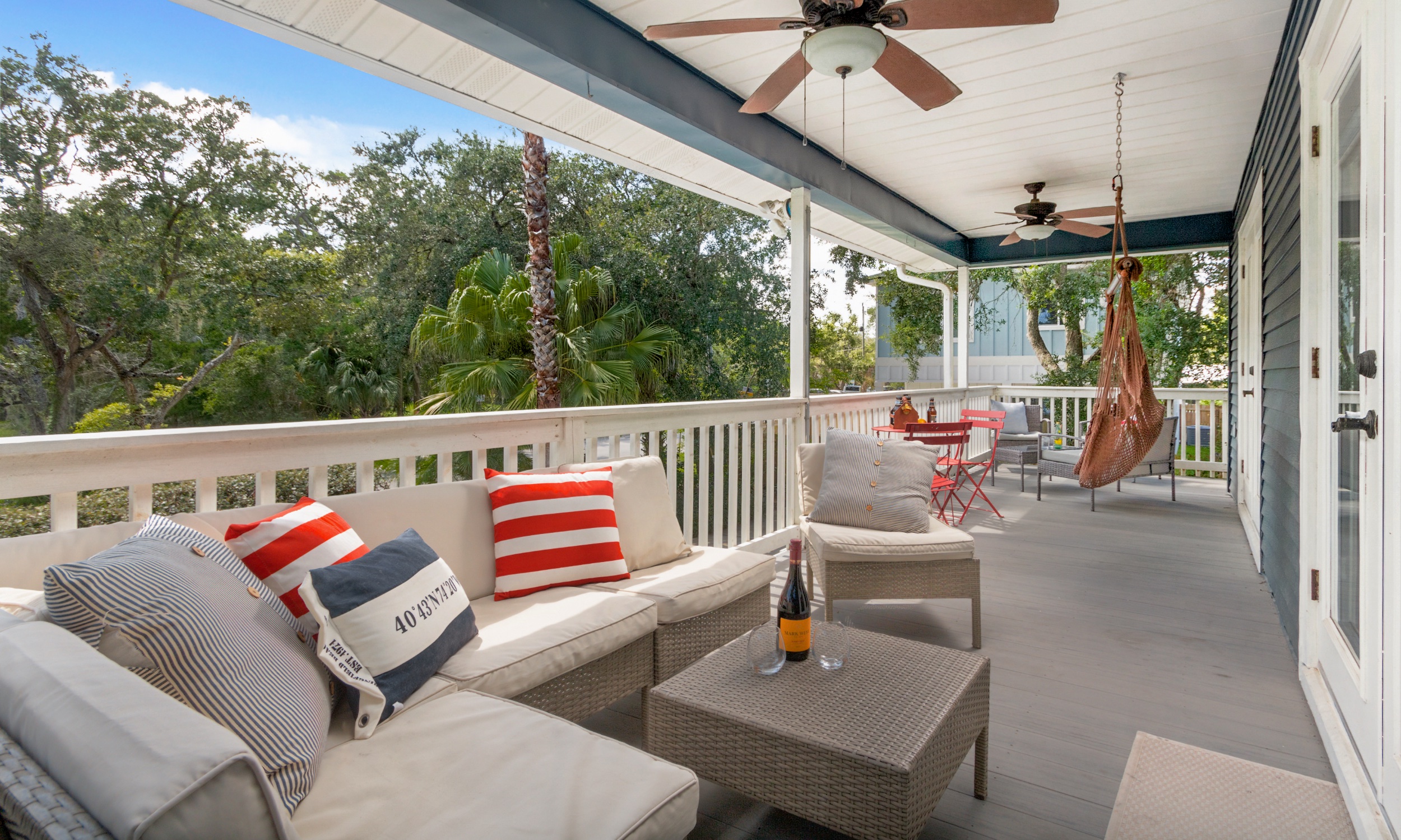 This porch has a recessed ceiling with fans, two seating areas, and a hanging chair