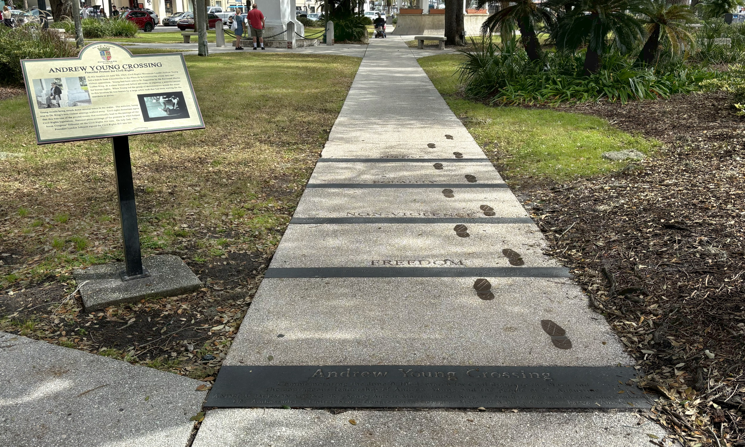 Footprint sculpture on a pavement with a sign next to it