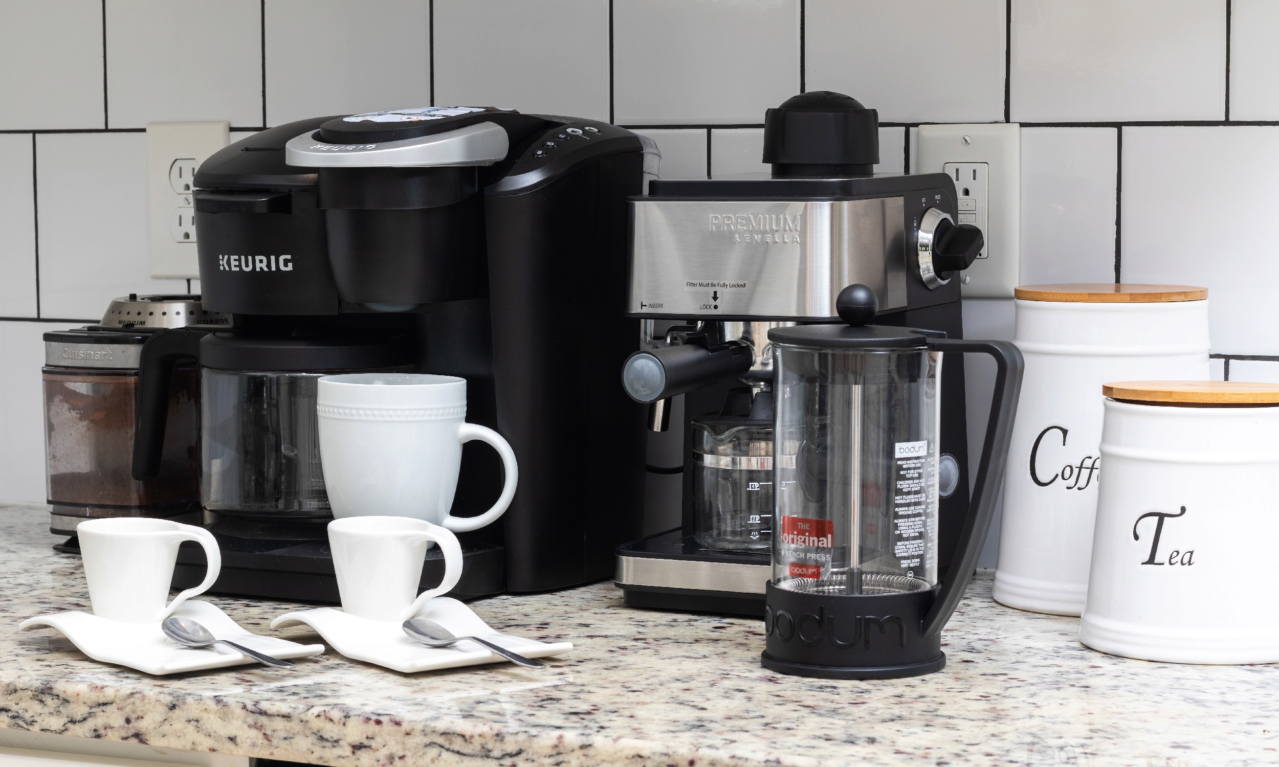 A coffee grinder and a plethora of coffee makers on a kitchen counter