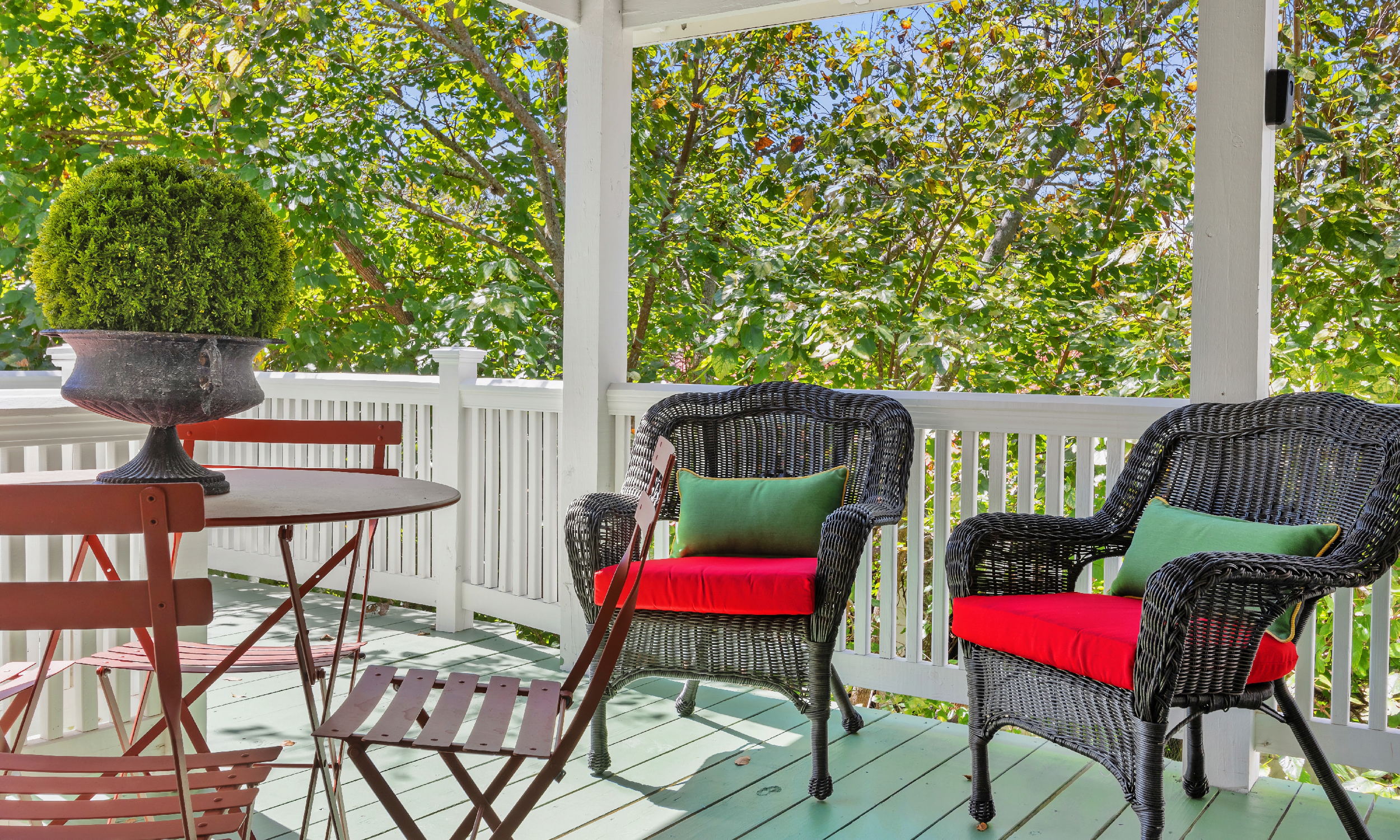 Two wicker chairs and a bistro table and chairs await guests in the upstairs retreate for two