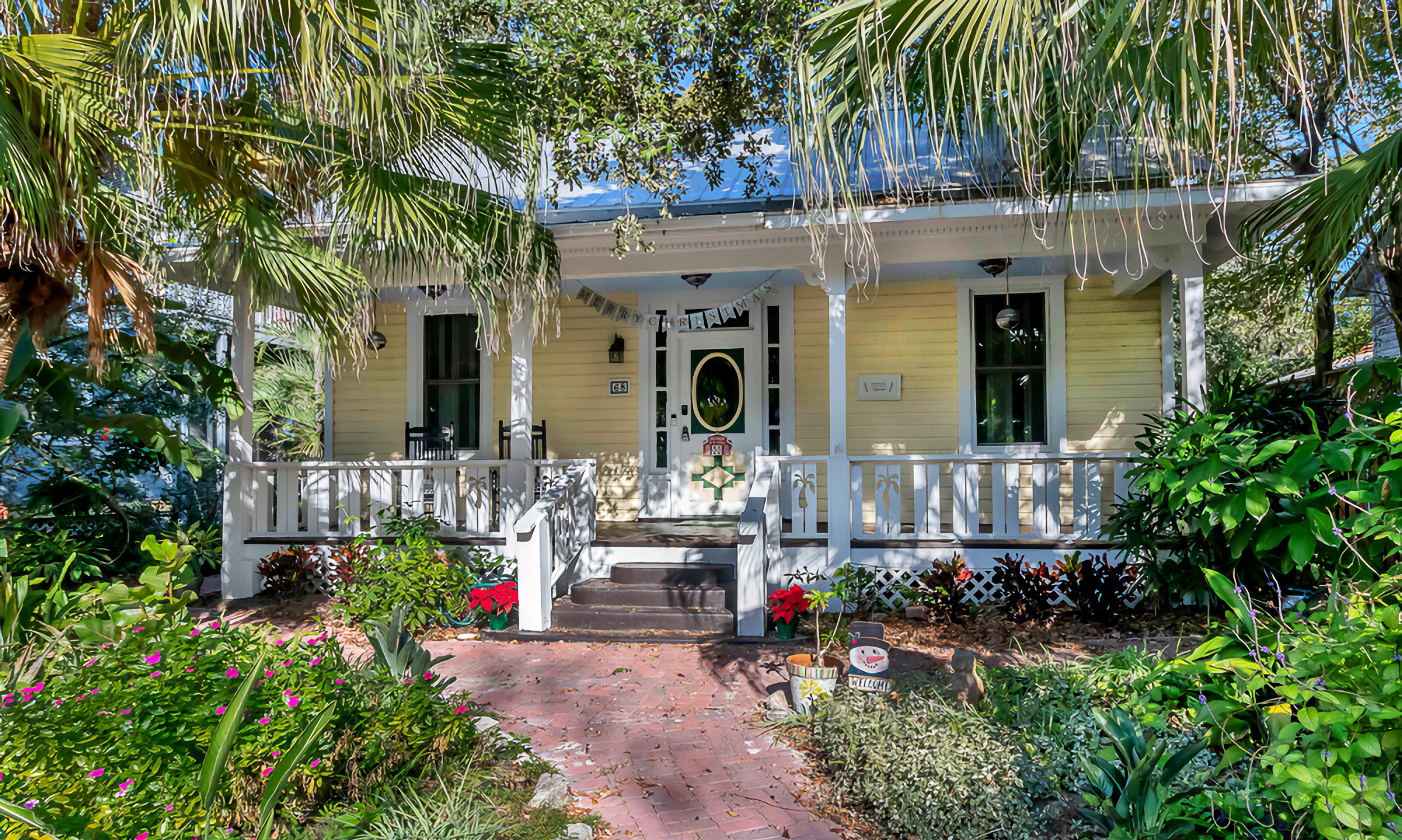 This charming yellow cottage in the historic district has a brick walk and white porch