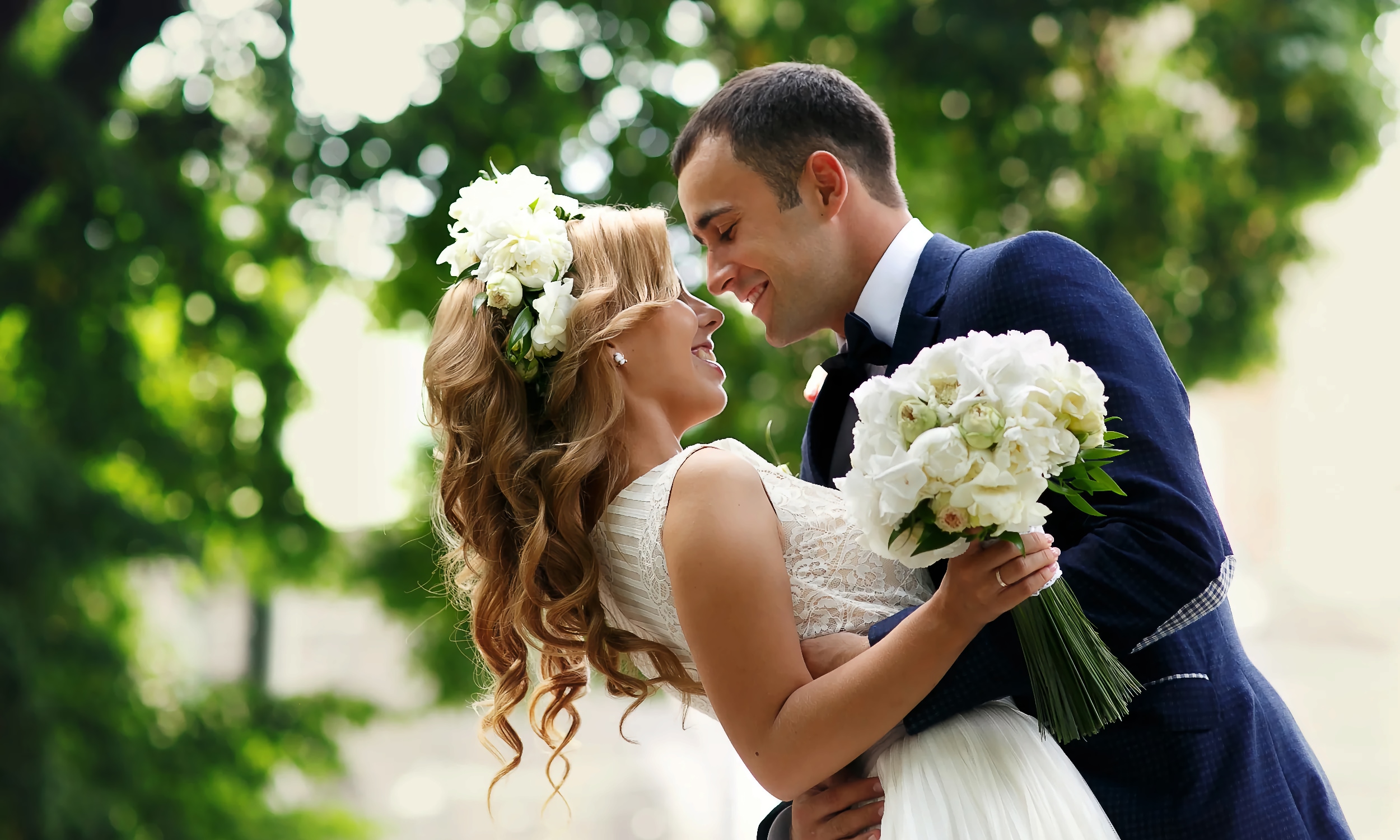 A bride and groom, embracing and smiling under a live oak tree at the Old Powder House Inn Bed and Breakfast