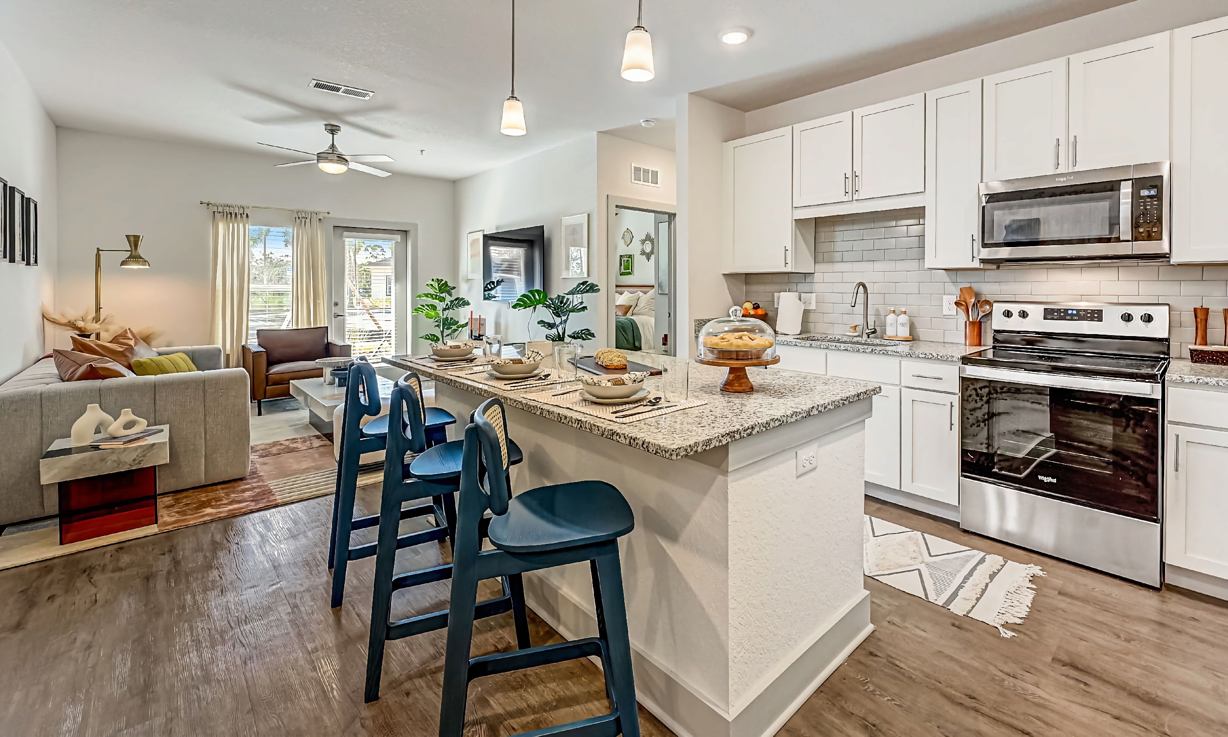 The kitchen, with generous island and living room beyond, in this apartment at Flagler Crossing 