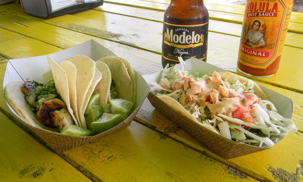 A table with a beer and two plates of tacos from Burrito Works Taco Shop in St. Augustine, Florida.