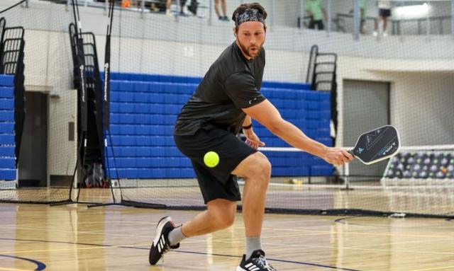 Pickleball player swinging at a ball with a backhand stroke