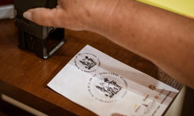 A person providing an offical stamp depicting the Cathedral Basilica to credential that someone has completed the First Coast Comino