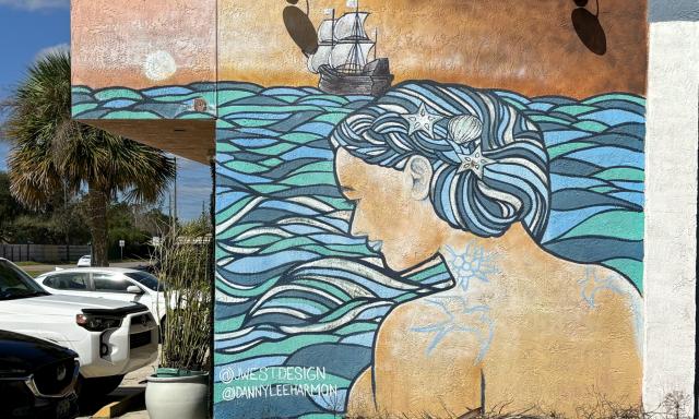 A mural of a mermaid looking at a pirate ship