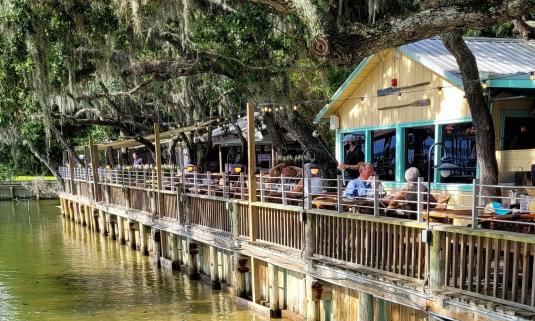 People eating on the deck by the water