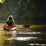 A woman kayaks on a river. 