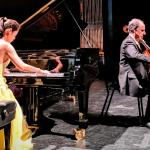 Dr. Catherine Lin, wearing in a yellow gown, plays the piano while Dr. Claudio Jaffe, plays the cello