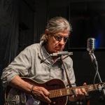 Singer and songwriter Denny Blue performing with guitar and harmonica. Courtesy of Terry Bottom