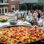 A large dish of paella at an outdoor party.