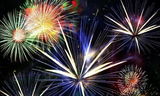 White and brilliantly colored fireworks erupt in a black sky