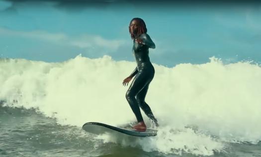 A Black woman surfing