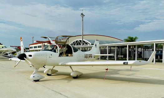 A white private plane, with open doors, on the tarmac at St. Auguste Airport