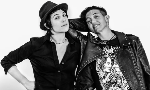 Bandmates from Ain't Sisters pose and smile in front of a white backdrop. 