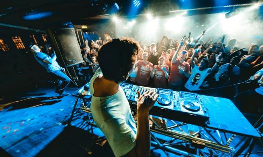 A crowd dances while the DJ fills the air with music.