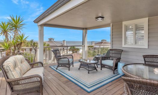 This deck as open and covered sitting areas with rattan furniture, and a lovely beach view