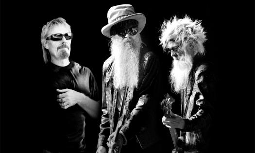 Bandmates from ZZ Top pose in front of a black backdrop.