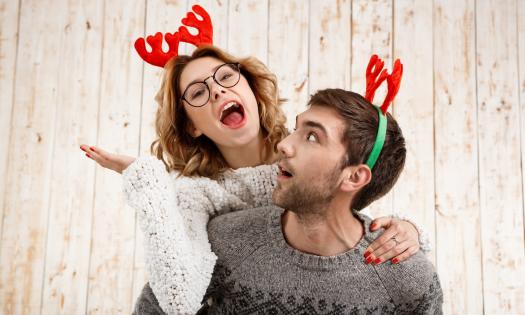 A couple in sweaters and reindeer ears playing together