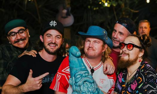 The five members of the band Bandfish, stand grouped together with one holding a teal green garden gnome