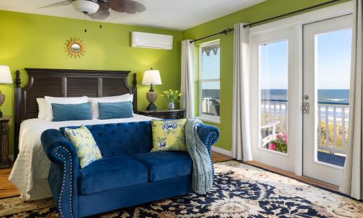 This stunning room features a bright green and royal blue decor and a wall of windows and doors to an ocean deck