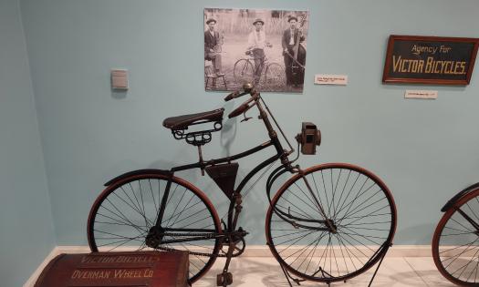 A vintage bicycle, made by Victor in a museum setting against a light blue wall