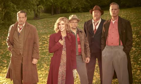 Alison Krauss smiles warmly, bundling her coat as she poses with her bandmates against the backdrop of a serene valley.