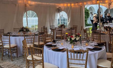 Round tables arranged for a lunch and learn event under a tent at Pena-Peck House