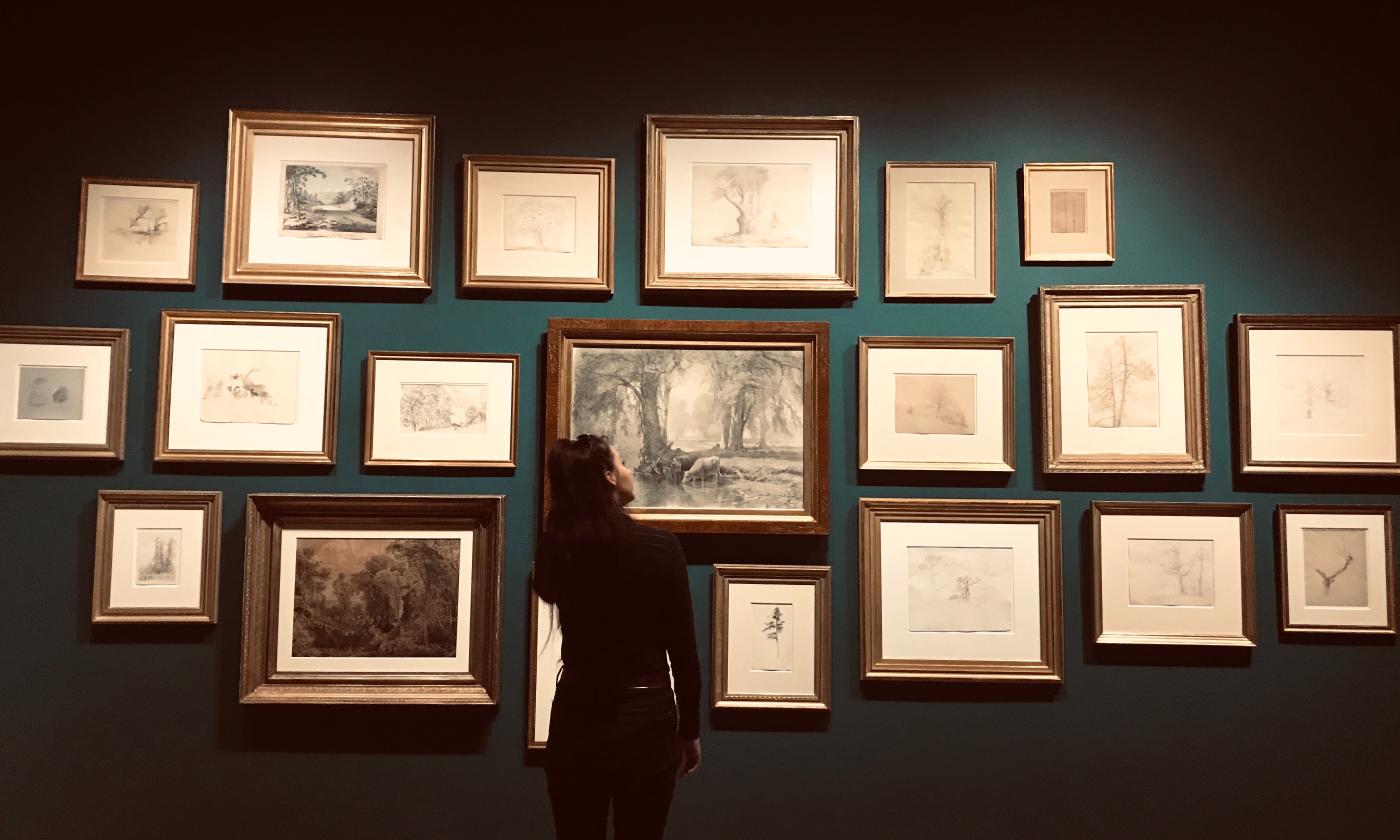 A woman stares at pictures in a gallery. 