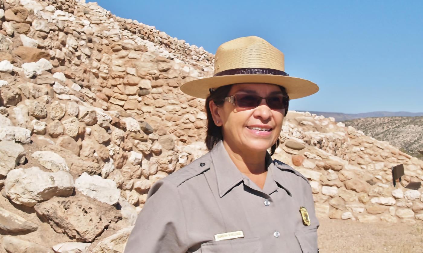 Dorothy FireCloud standing in front of rocks in a desert area. 