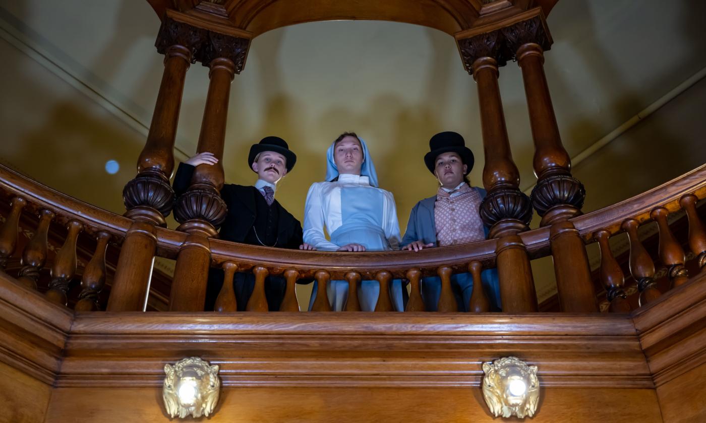 Flagler College students standing above a balcony looking over it with scowls on their faces while portraying characters in Shakespeare's Measure For Measure. 