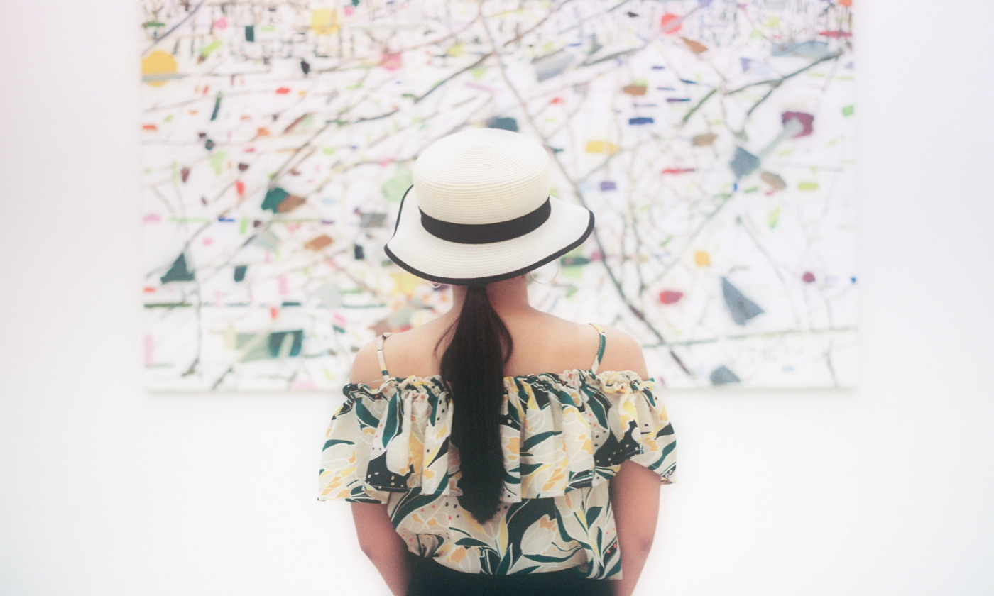 A woman stares at a picture in a gallery. 