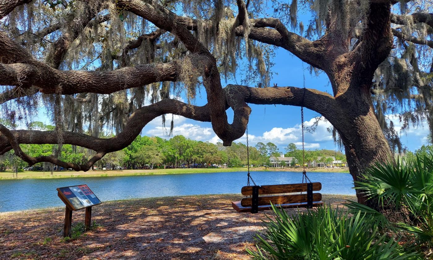 A trail along a river, with a bench swing and information about the area