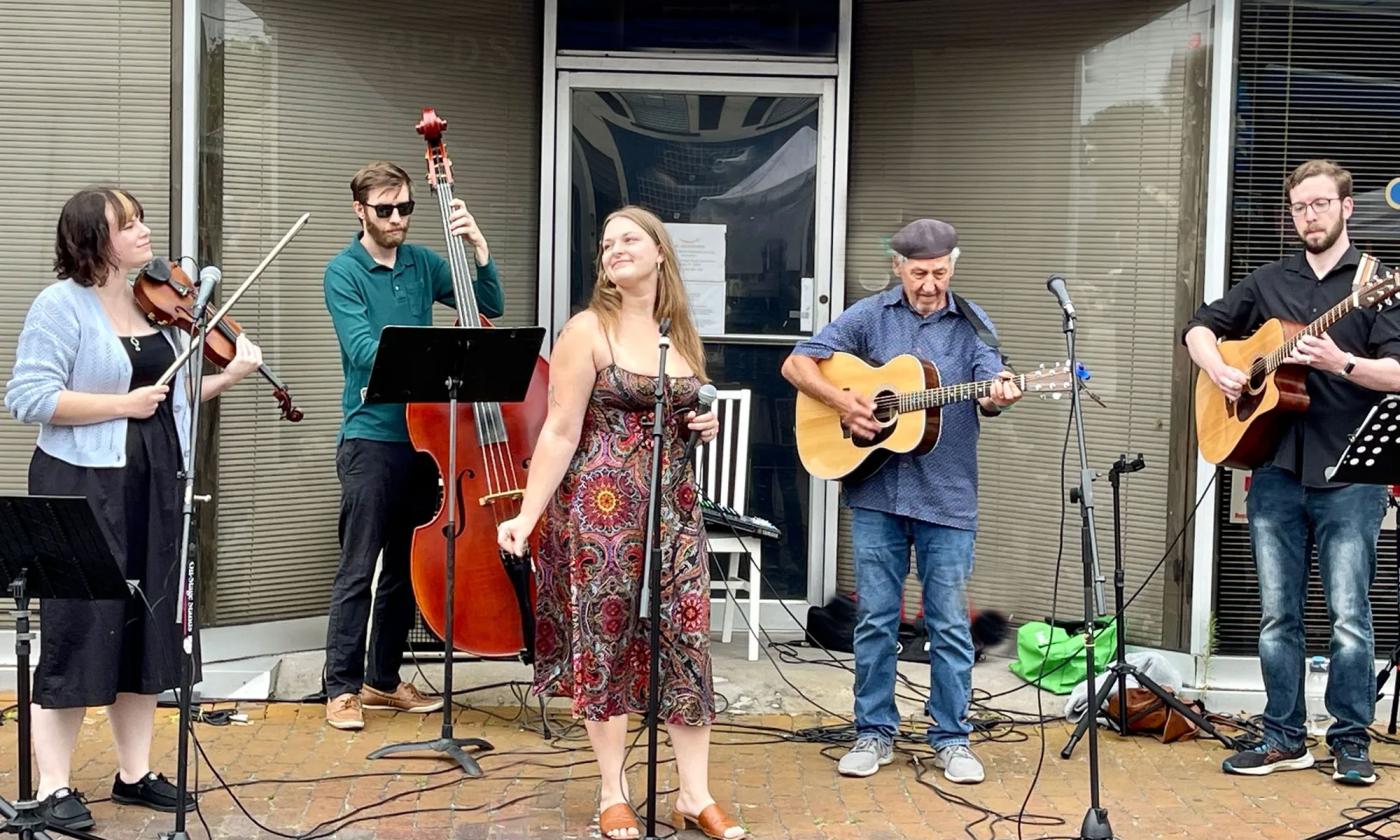 The band AMple Angst performing at a storefront in daytime. 