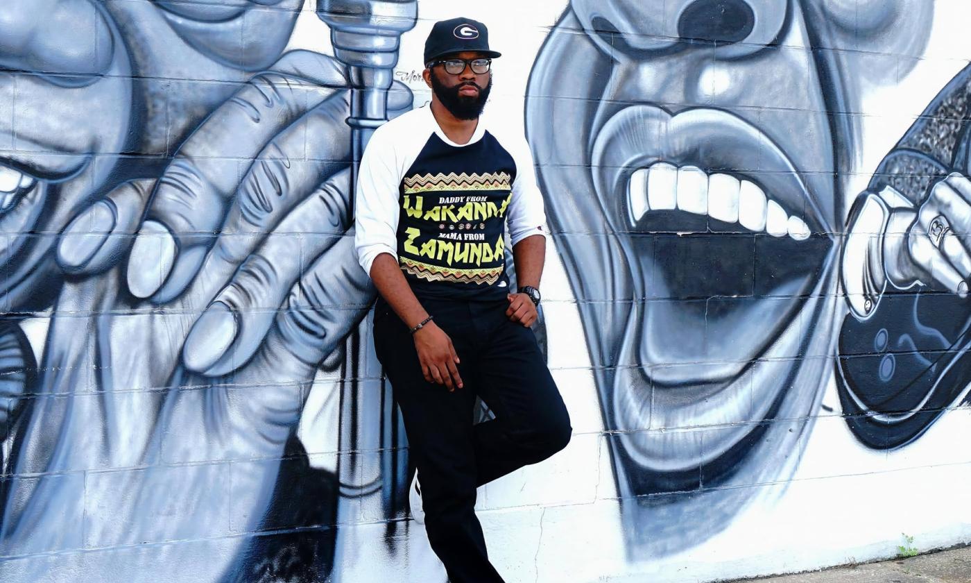 Hip-hop artist Jamal Steele standing in front of a mural