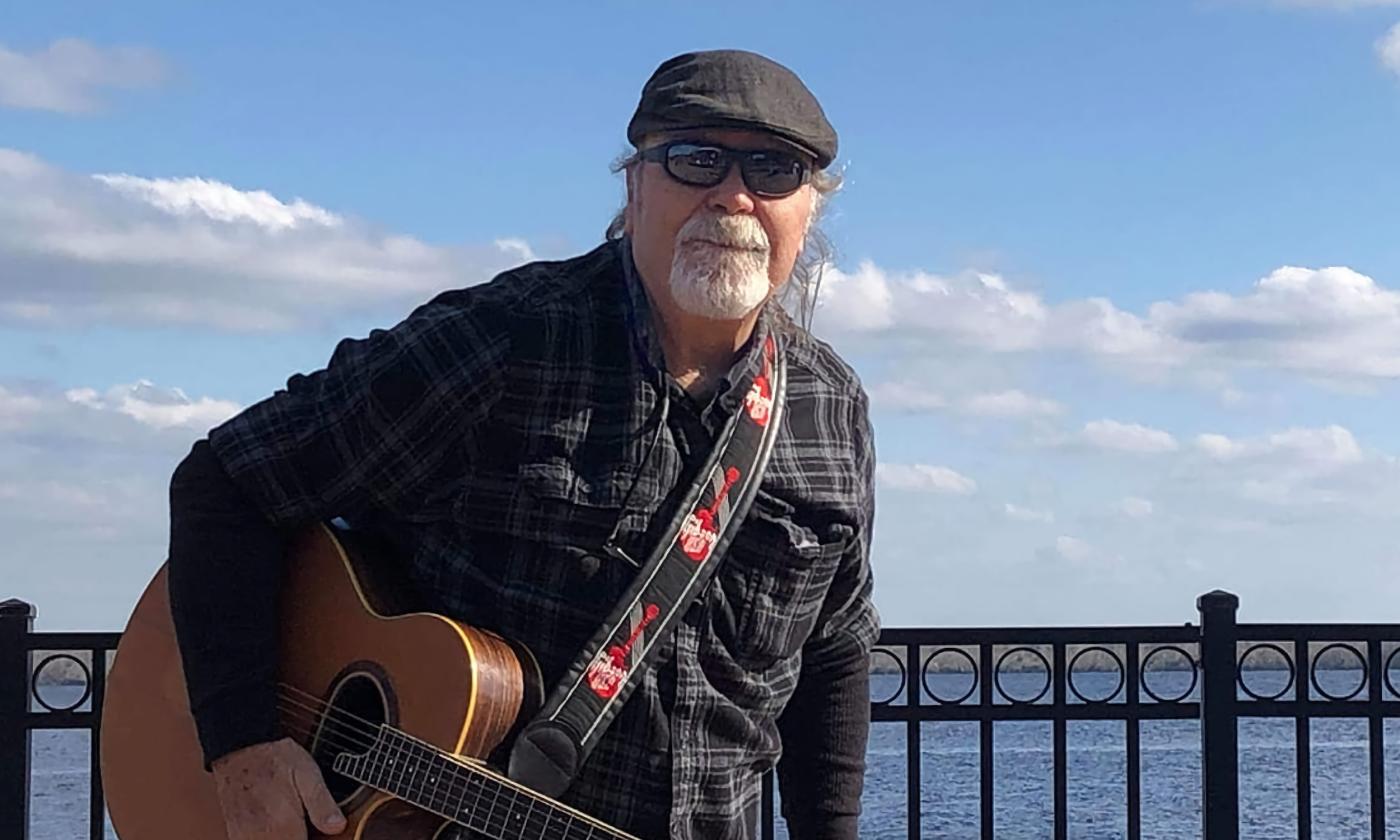 Sweet William Ennis, standing by the river with his guitar hanging from its strap