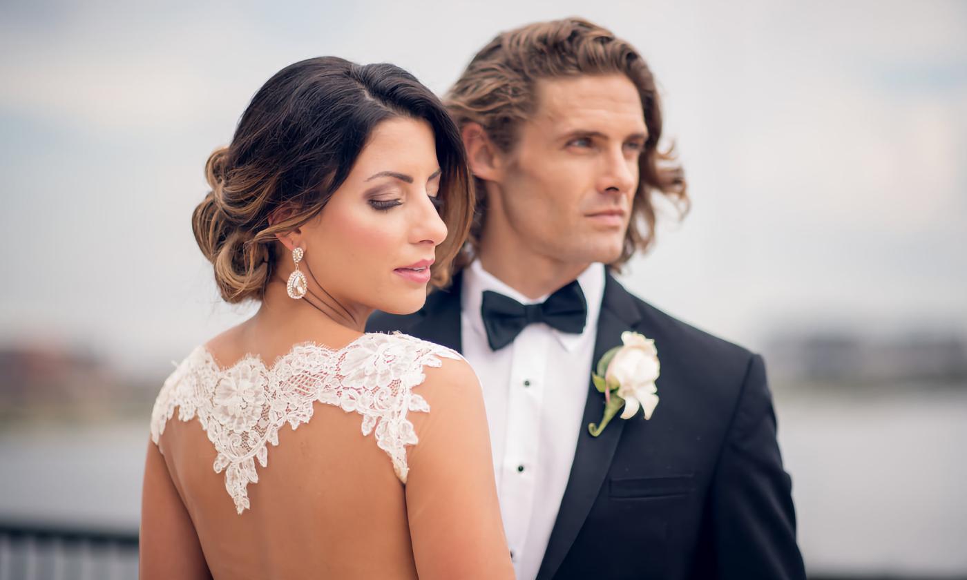 Bride with open-back dress posing with groom in black tuxedo