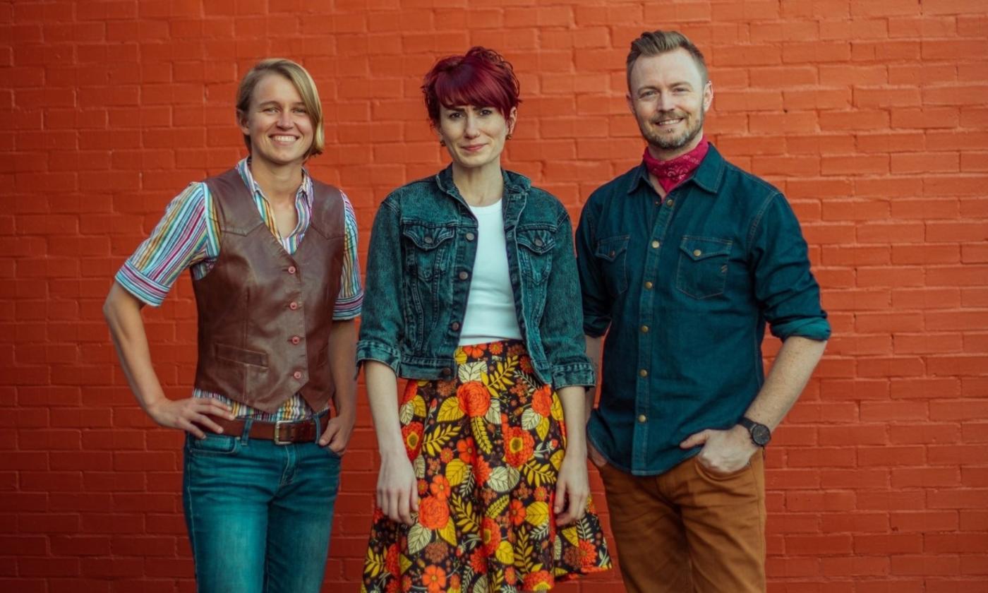 Bandmates from House of Hamill pose in front of an orange brick wall. 