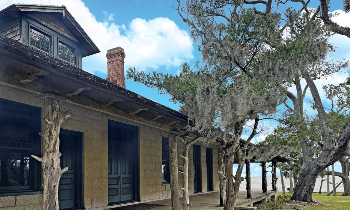 The porch of the Princess Place lodge is braced by tree trunks and shaded by live oaks.